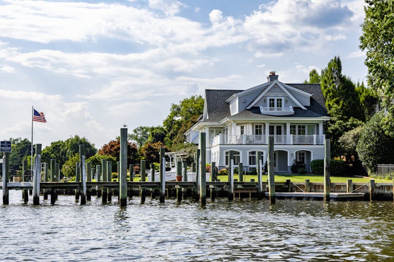 A lovely waterfront home with a dock and American flag on a sunny summer day.